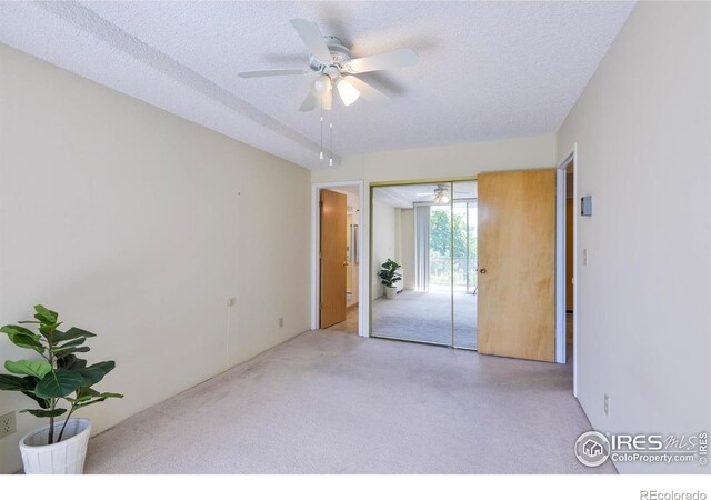 carpeted spare room featuring a textured ceiling and ceiling fan