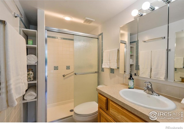 bathroom with toilet, vanity, visible vents, and a stall shower