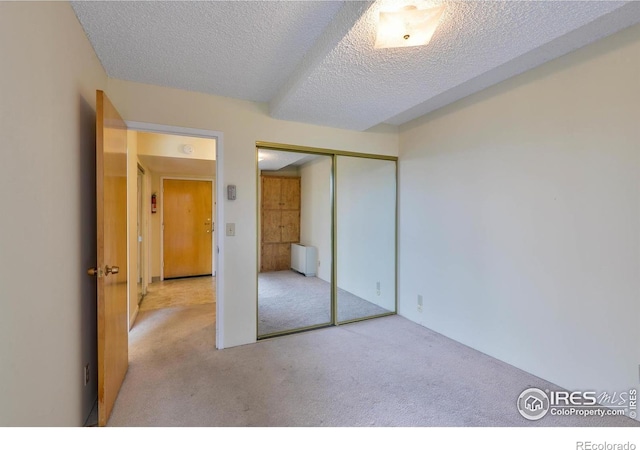 unfurnished bedroom with a closet, carpet flooring, a textured ceiling, and radiator heating unit