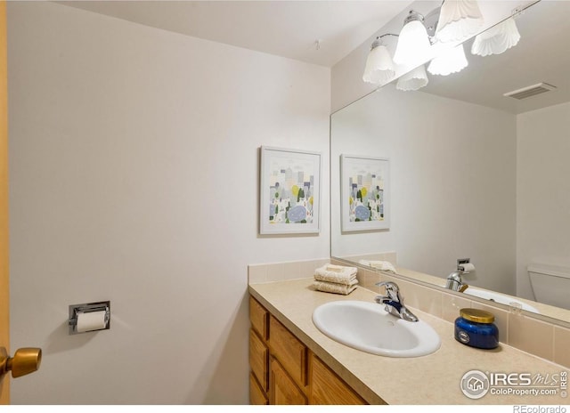 half bathroom featuring visible vents, toilet, and vanity