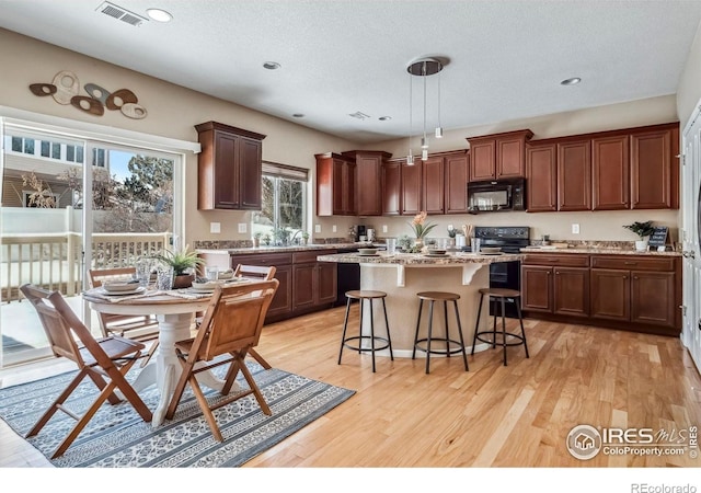 5036 Ridgewood Dr, Johnstown, CO 80534 - kitchen featuring black microwave, visible vents, a center island, electric stove, and a breakfast bar area