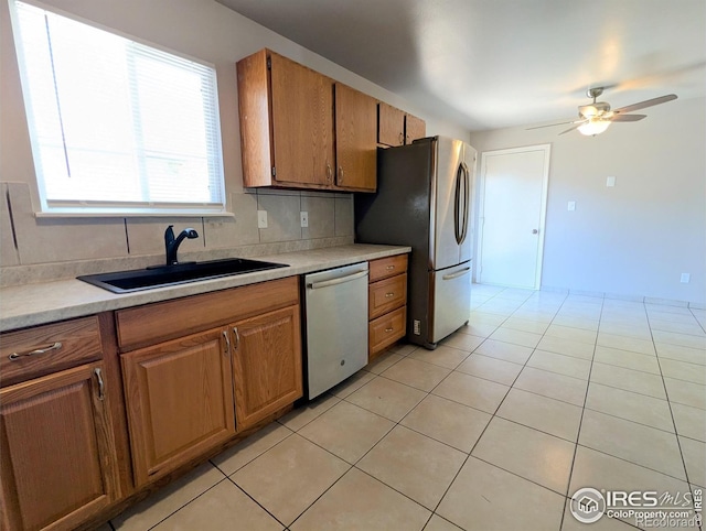kitchen with light countertops, a ceiling fan, brown cabinets, appliances with stainless steel finishes, and a sink