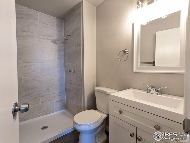 bathroom with tiled shower, vanity, and toilet