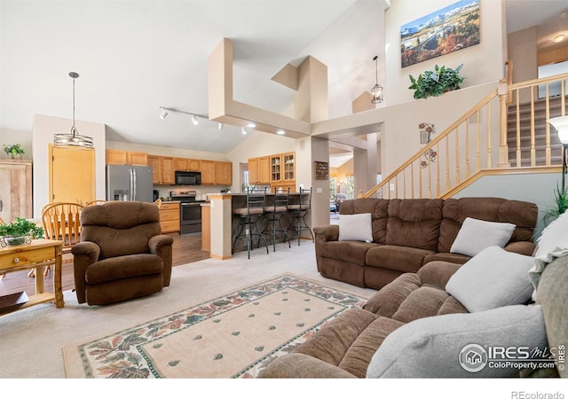 461 Scenic Dr, Loveland, CO 80537 - living room with light colored carpet, stairs, and high vaulted ceiling