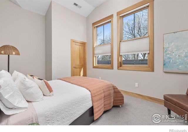 carpeted bedroom with baseboards, visible vents, and vaulted ceiling