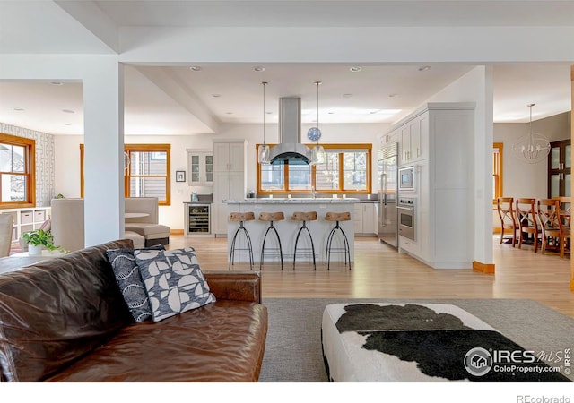 living area featuring an inviting chandelier, recessed lighting, light wood finished floors, and wine cooler