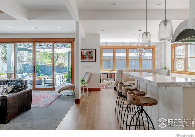 kitchen with light wood finished floors, a breakfast bar area, french doors, open floor plan, and pendant lighting