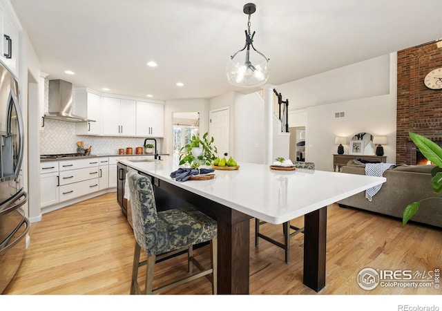 4939 Yoke Ct, Loveland, CO 80537 - kitchen with wall chimney range hood, a sink, stainless steel appliances, light wood finished floors, and backsplash