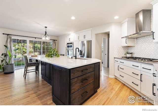 4939 Yoke Ct, Loveland, CO 80537 - kitchen with wall chimney exhaust hood, appliances with stainless steel finishes, a sink, white cabinetry, and decorative backsplash