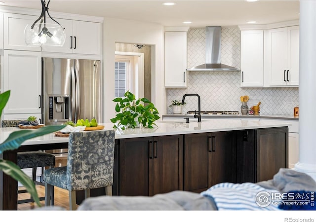 4939 Yoke Ct, Loveland, CO 80537 - kitchen with wall chimney range hood, stainless steel refrigerator with ice dispenser, light countertops, decorative backsplash, and white cabinets