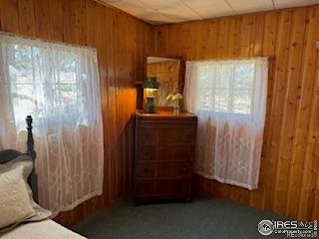 carpeted bedroom featuring wood walls