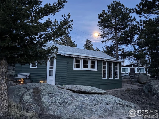 view of side of home with roof with shingles and log veneer siding