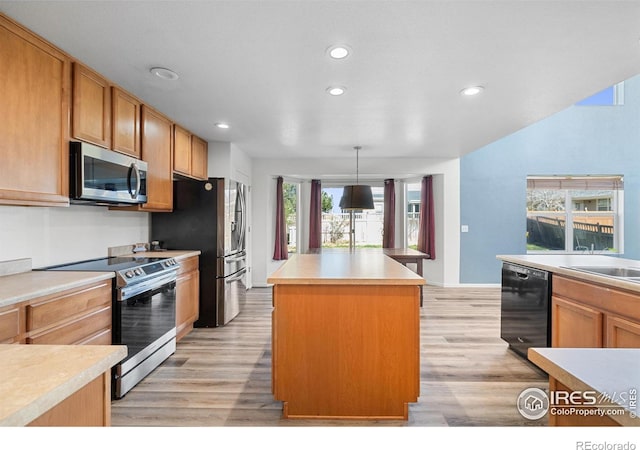 kitchen with recessed lighting, a center island, light countertops, appliances with stainless steel finishes, and light wood finished floors