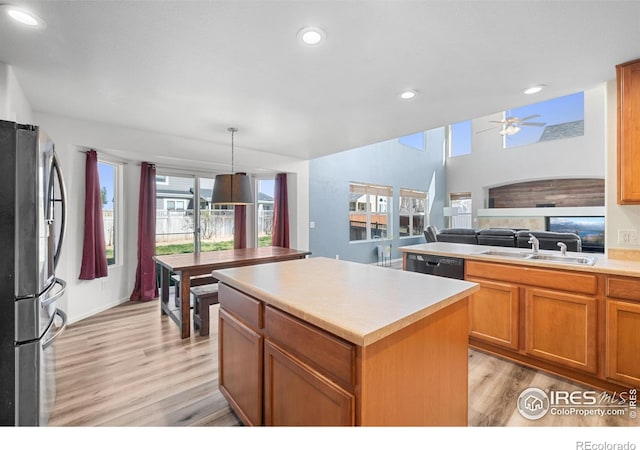 kitchen with plenty of natural light, freestanding refrigerator, light wood finished floors, dishwasher, and a sink