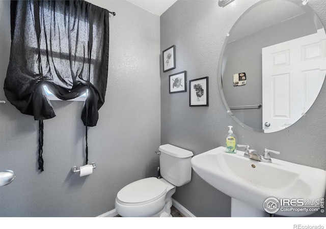 bathroom with baseboards, a sink, and toilet