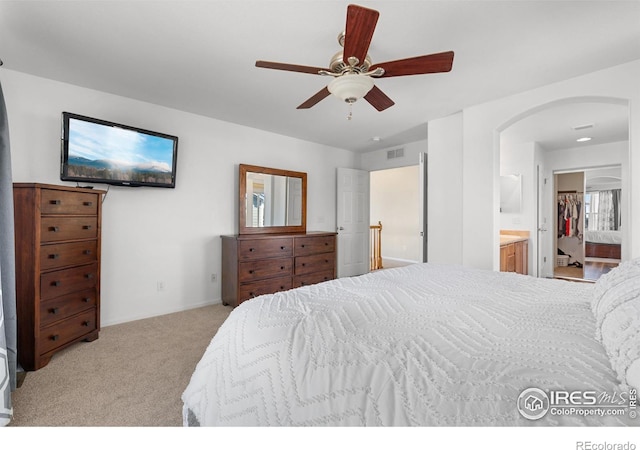 bedroom with carpet, connected bathroom, arched walkways, a ceiling fan, and visible vents