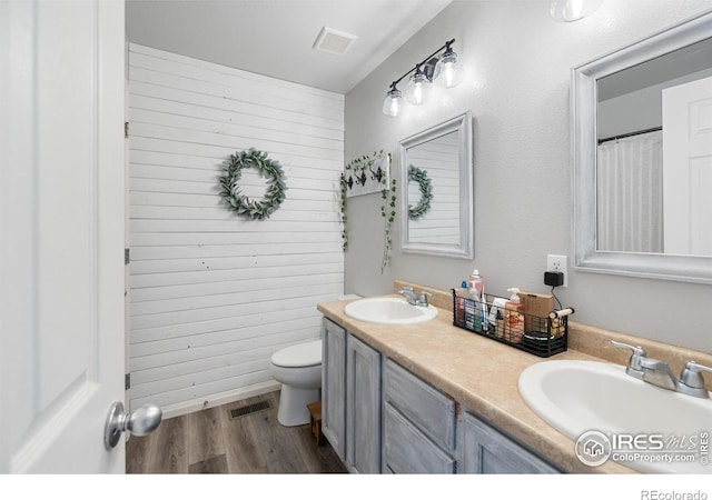 bathroom with a sink, visible vents, toilet, and wood finished floors