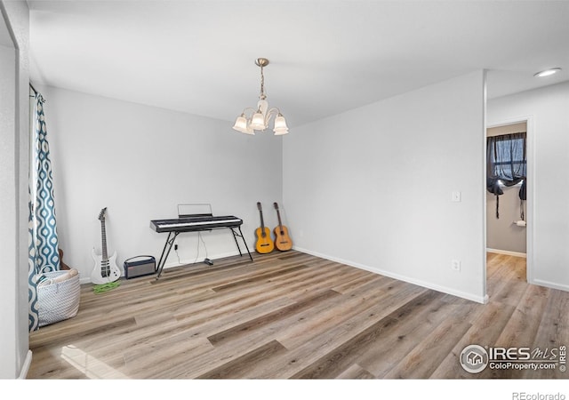 interior space with baseboards, an inviting chandelier, and wood finished floors
