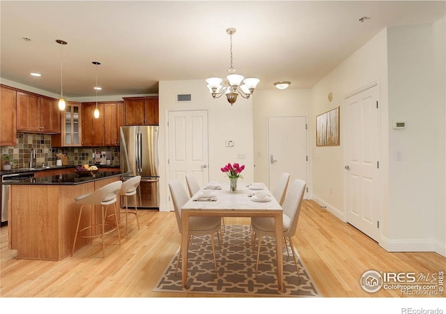 dining area featuring visible vents, baseboards, light wood-type flooring, and a notable chandelier