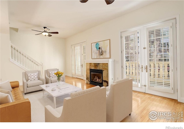 living room with a wealth of natural light, stairs, wood-type flooring, and ceiling fan