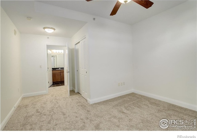 spare room with light carpet, baseboards, and a ceiling fan