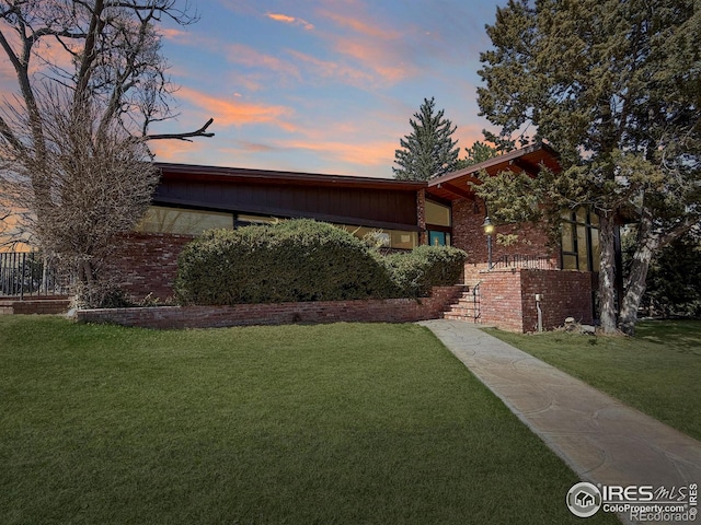 view of front of property featuring brick siding and a yard
