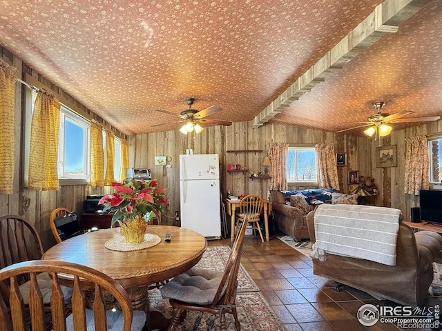 dining area featuring wooden walls and ceiling fan