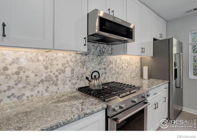 609 Hummer Dr, Nederland, CO 80466 - kitchen with appliances with stainless steel finishes, decorative backsplash, white cabinetry, and visible vents
