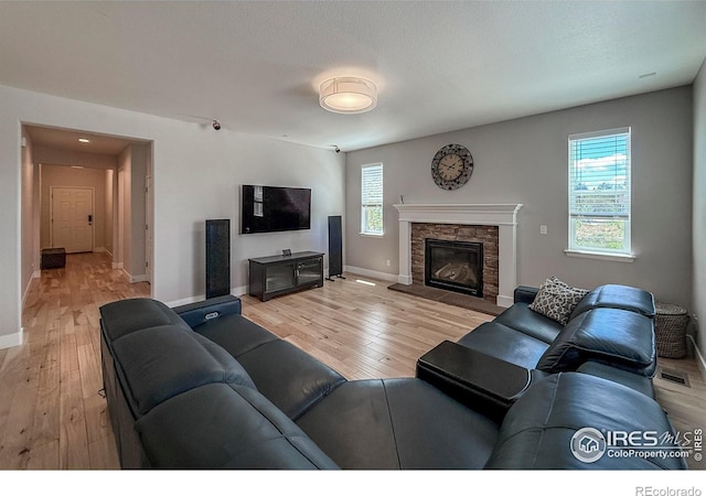 living room featuring light wood-style floors, baseboards, and a fireplace