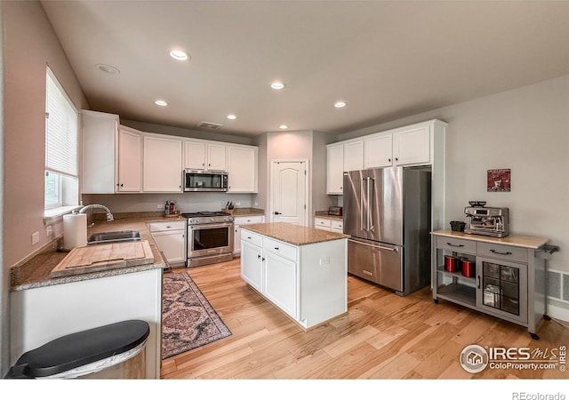 kitchen featuring stainless steel appliances, a sink, light wood-type flooring, white cabinets, and recessed lighting