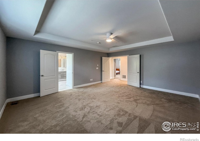 unfurnished bedroom featuring a tray ceiling, baseboards, carpet flooring, and connected bathroom