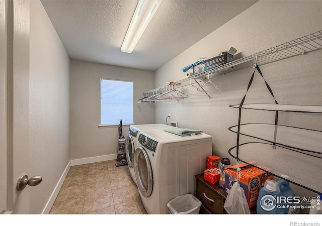 washroom with washer and clothes dryer, a textured ceiling, and baseboards