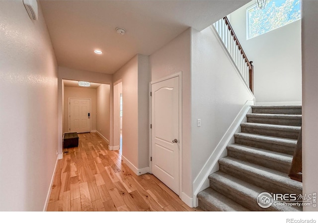 corridor featuring light wood-style flooring, stairs, baseboards, and recessed lighting