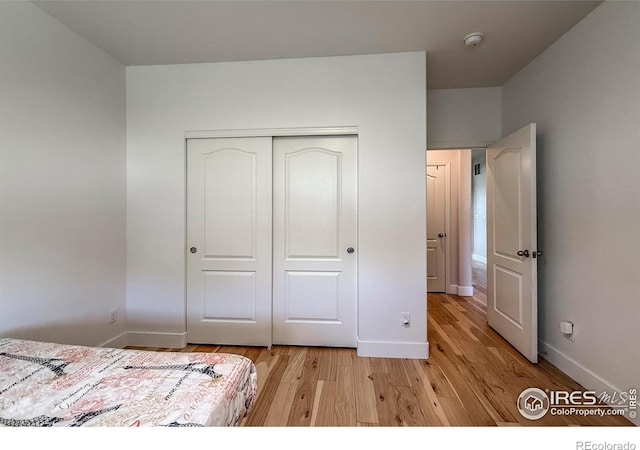 bedroom featuring light wood-type flooring, a closet, and baseboards