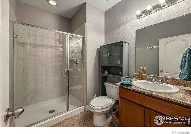 bathroom with tile patterned flooring, toilet, a shower stall, and vanity