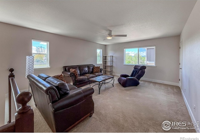 living area featuring carpet flooring, ceiling fan, baseboards, and a textured ceiling