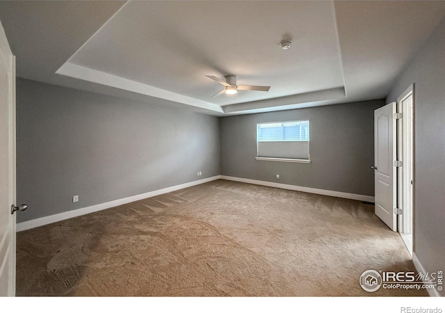 unfurnished bedroom featuring a raised ceiling, carpet flooring, and baseboards