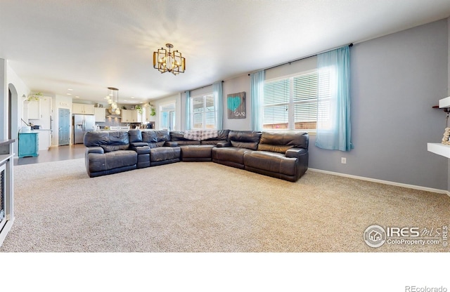 living area featuring a chandelier, carpet flooring, and baseboards