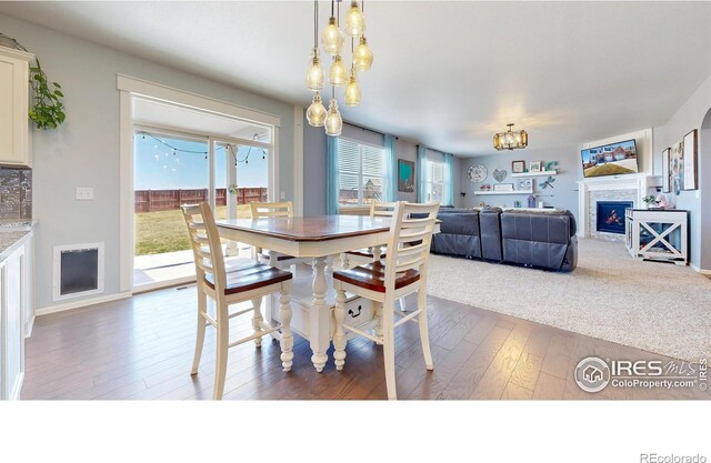 dining space with a chandelier, hardwood / wood-style flooring, and a lit fireplace