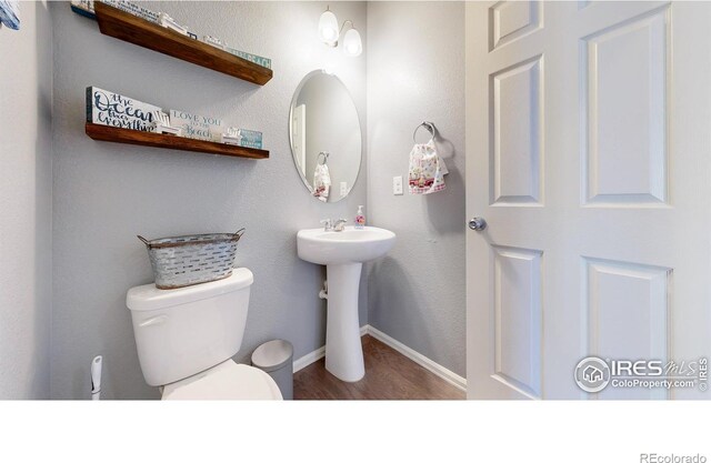 bathroom featuring toilet, wood finished floors, and baseboards