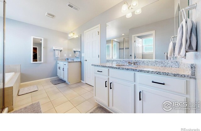 bathroom featuring two vanities, a stall shower, tile patterned flooring, baseboards, and a tub