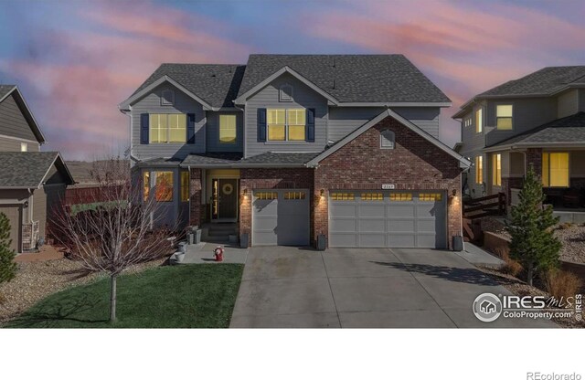 traditional home featuring a garage, brick siding, driveway, and roof with shingles