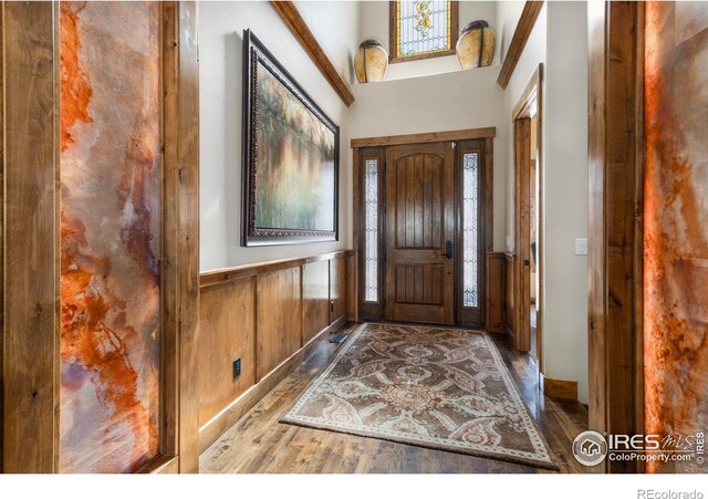 entryway with wooden walls, a wainscoted wall, wood finished floors, and baseboards
