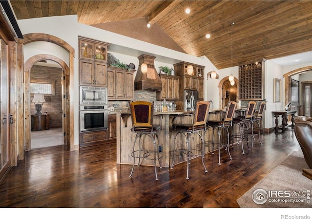 kitchen featuring arched walkways, custom exhaust hood, dark wood-style flooring, and stainless steel appliances