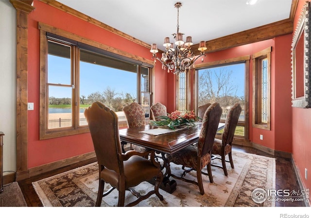 dining area with a water view, a notable chandelier, baseboards, and wood finished floors