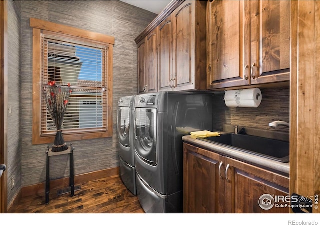 laundry area featuring baseboards, dark wood-type flooring, independent washer and dryer, cabinet space, and a sink