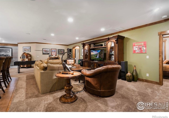 living area with ornamental molding, recessed lighting, arched walkways, and light colored carpet