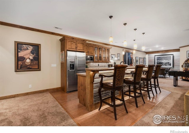 kitchen with stainless steel appliances, glass insert cabinets, a kitchen bar, and brown cabinetry