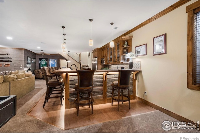 bar with baseboards, wet bar, appliances with stainless steel finishes, pendant lighting, and ceiling fan