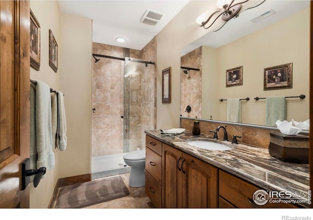 bathroom with a tile shower, vanity, visible vents, and toilet